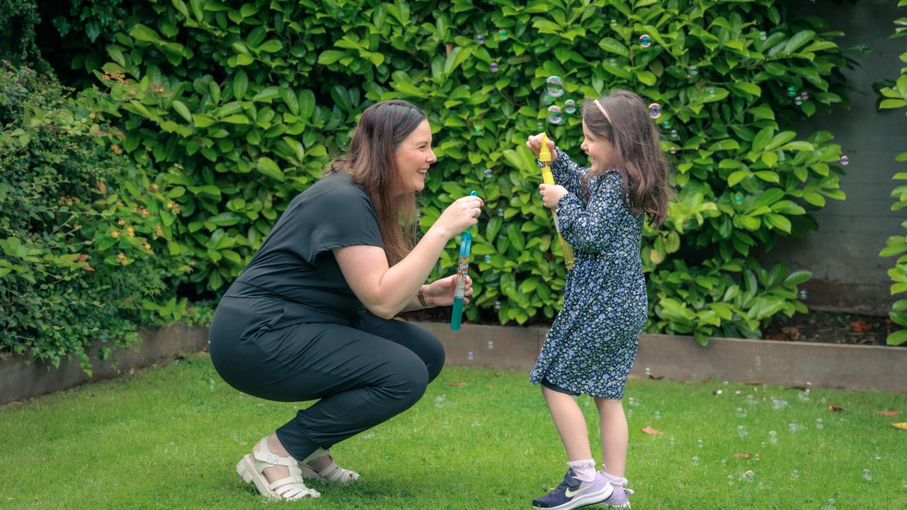 parent and child playing with bubbles in garden