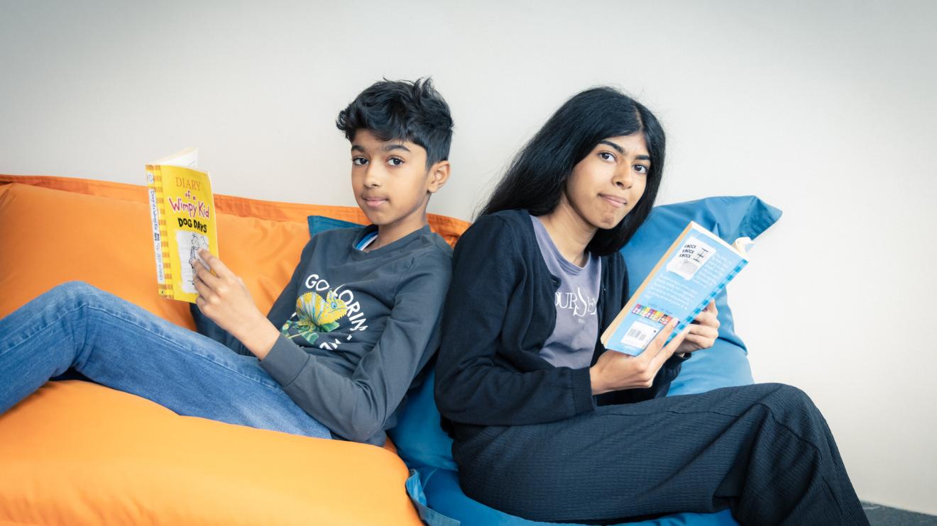 two children sitting on beanbags reading together