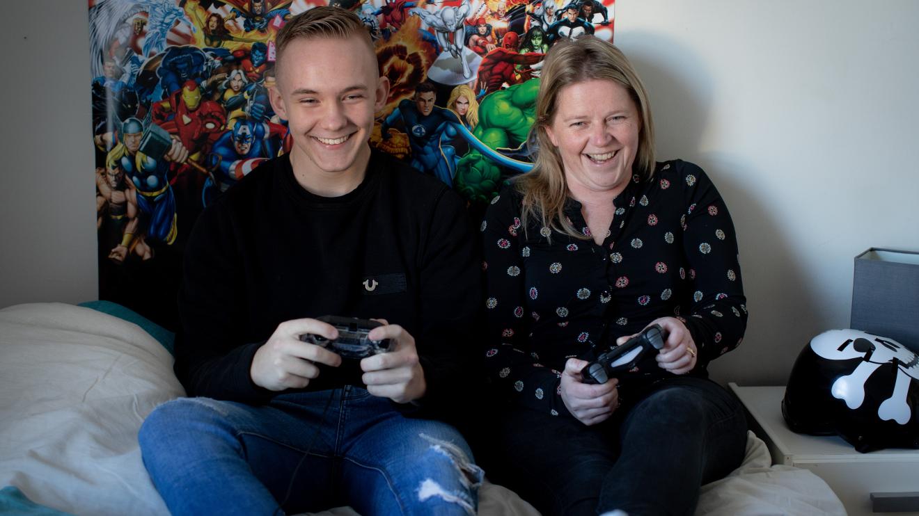An older teenager playing a video game with his foster carer / adopter