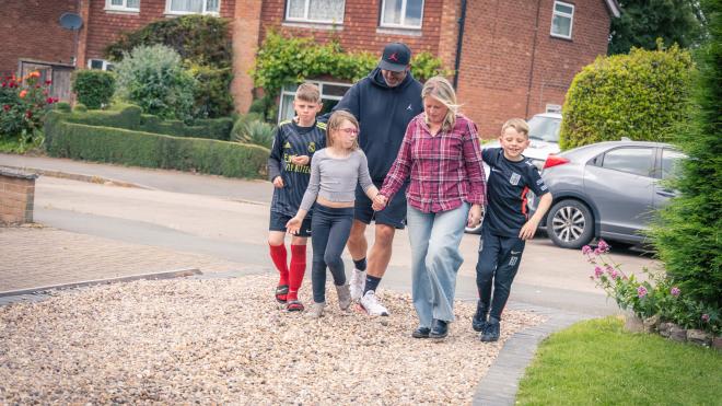 family of five walking up house driveway