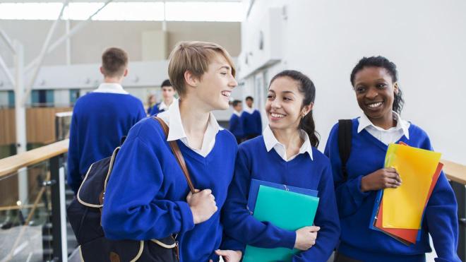 Three smiling school pupils with books 