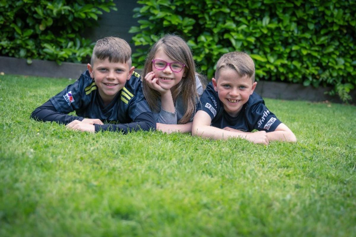 Three children lying in the garden smiling